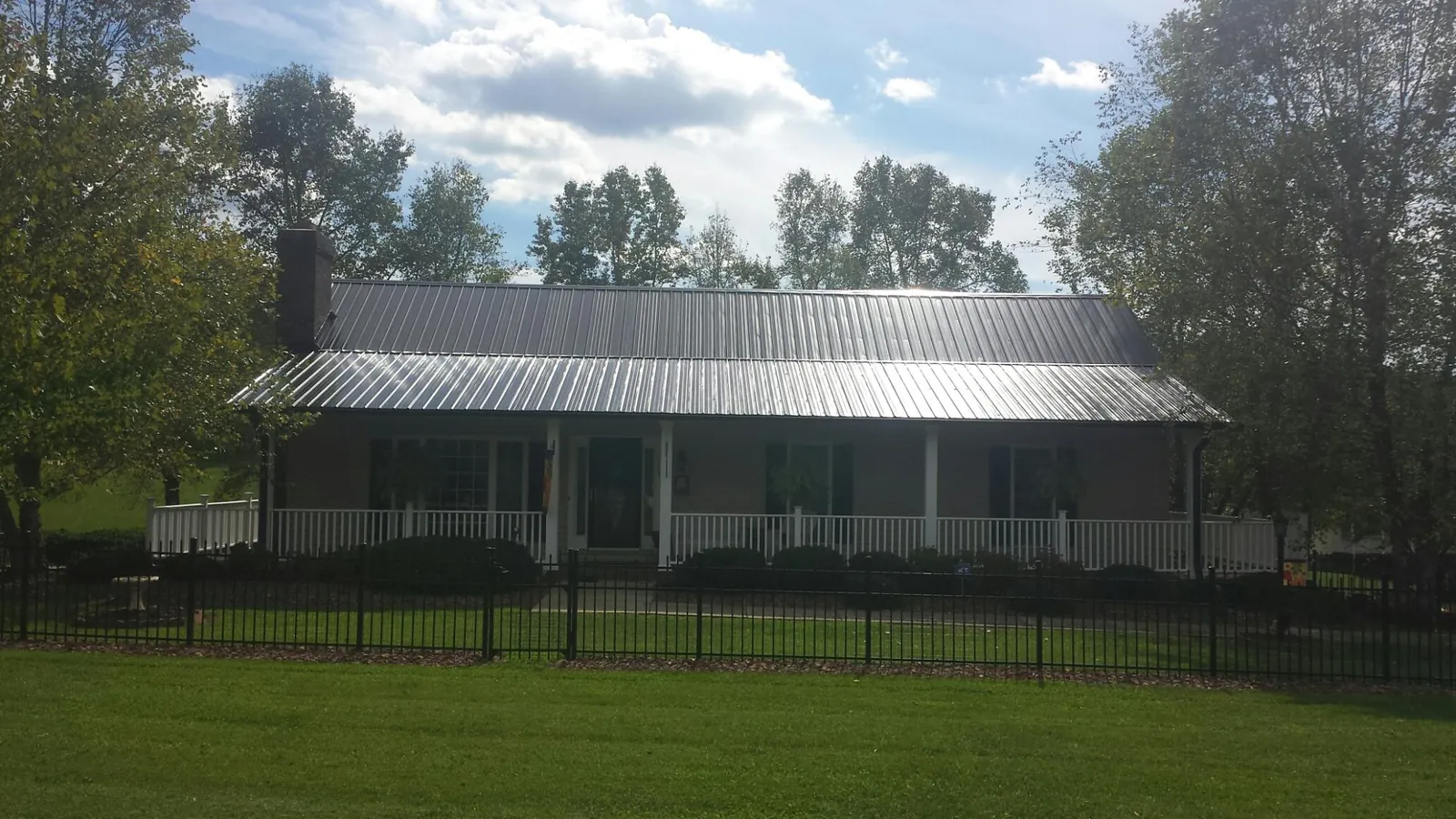 Gray metal roof on a brick ranch with a full width front porch — Gutter Guard Installation work by our crew in Sardis